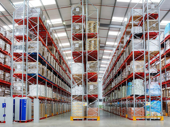 Vista interior de un moderno almacén con estructura de acero ligero, con estanterías altas de almacenamiento, pallets organizados y uso eficiente del espacio vertical.