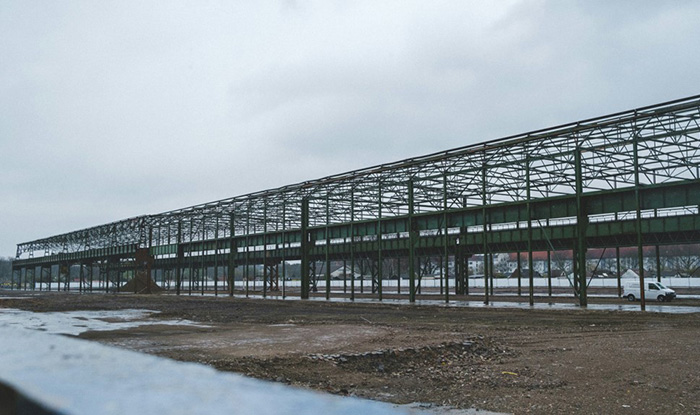 Estructura de almacén de acero en construcción con vigas estructurales expuestas en un sitio abierto.