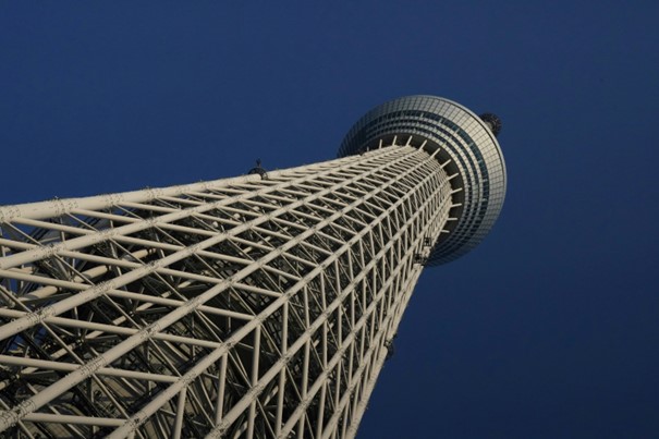 Cúpula moderna de acero y vidrio con estructura circular en capas y pasillos interiores, frente a un cielo azul claro.